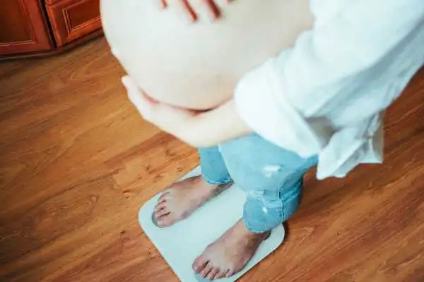 Image of woman weighing herself and experiencing weight gain through pregnancy Springs Mire